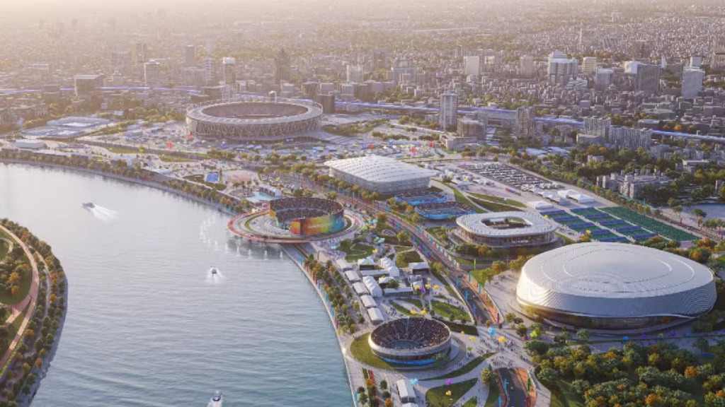 A high-angle view of a modern Indian cityscape featuring new metro lines and highway interchanges, symbolizing the infrastructure execution and urban modernization readiness for the 2030 Commonwealth Games.